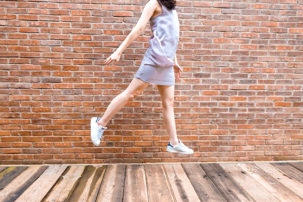 woman in white tank top and blue denim shorts standing on brown wooden floor